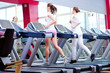Photo: Two young sporty women run on machine Two young sporty women run on machine