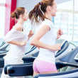 Photo: Two young sporty women run on machine Two young sporty women run on machine