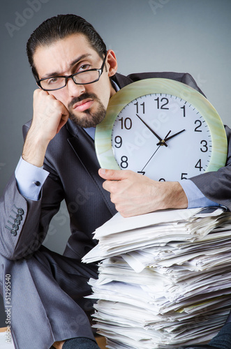 Photo: Man with clock and pile of papers Man with clock and pile of papers