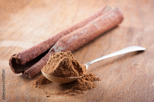 Photo: Cinnamon powder on a spoon with a stick of natural cinnamon Cinnamon powder on a spoon with a stick of natural cinnamon