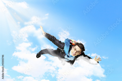 Photo: Young businessman flying with parachute on back Young businessman flying with parachute on back