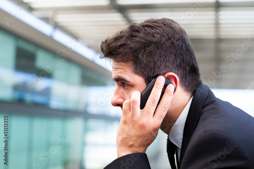 Photo: Closeup portrait of handsome business man using cell phone at th Closeup portrait of handsome business man using cell phone at th