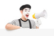 Male mime artist holding a loudspeaker and posing on a blank pan