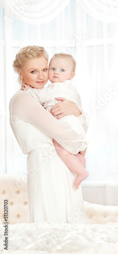 Photo: young mother with a baby in a beautiful bedroom young mother with a baby in a beautiful bedroom