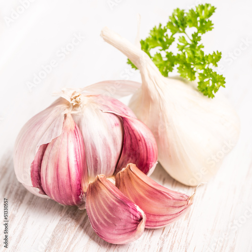 Photo: Knoblauch (Allium sativum) mit Petersilie auf hellem Holz Knoblauch (Allium sativum) mit Petersilie auf hellem Holz
