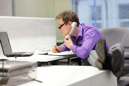 Photo: businessman on phone looking at screen - bad sitting posture businessman on phone looking at screen - bad sitting posture