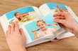 Photos in hands and photo album on wooden table