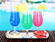 Photo: Glasses of cocktails on table near pool Glasses of cocktails on table near pool