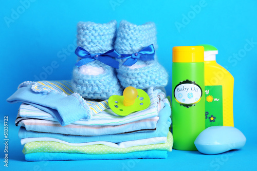 Photo: Pile of baby clothes on blue background Pile of baby clothes on blue background