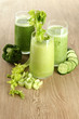 Glasses of green vegetable juice on wooden background