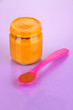 Baby food with weaning spoon on purple background