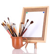 Small easel with sheet of paper and art supplies isolated