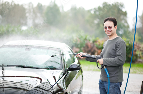 Photo: Young man washing his car with compression water Young man washing his car with compression water