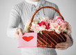 man holding basket full of flowers and postcard