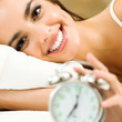 Woman with alarmclock on the bed