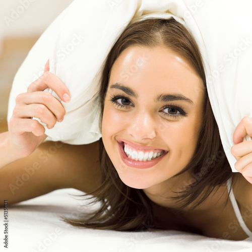 Photo: Young woman waking up on bed Young woman waking up on bed