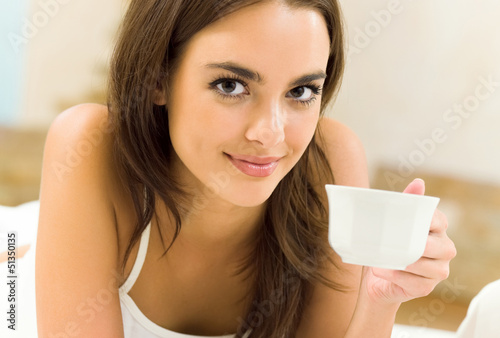 Photo: Young happy smiling woman drinking coffee, at home Young happy smiling woman drinking coffee, at home