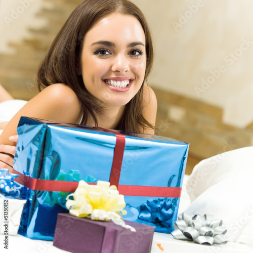 Photo: Happy smiling woman with gifts at home Happy smiling woman with gifts at home