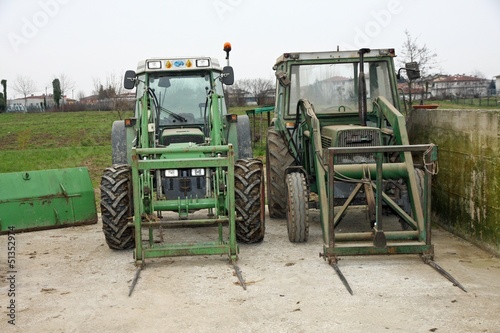 Photo: two green tractors parked on a farm outdoors two green tractors parked on a farm outdoors