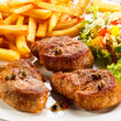 Grilled steaks, French fries and vegetables