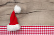 Weihnachtskarte mit einer roten Zipfelmütze auf Holz kariert
