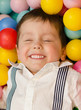 Smiling little boy lying in colorful balls