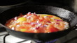 Egg frying in a pan. Adding onion slices.