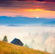 foggy landscape with an old barn in the mountains at the summer