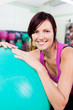 lächelnde frau mit gymnastikball im studio