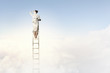 Businesswoman standing on ladder