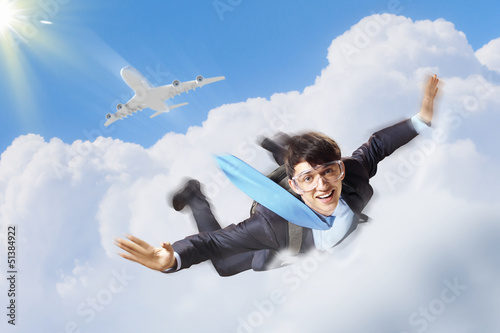 Photo: Young businessman flying with parachute on back Young businessman flying with parachute on back