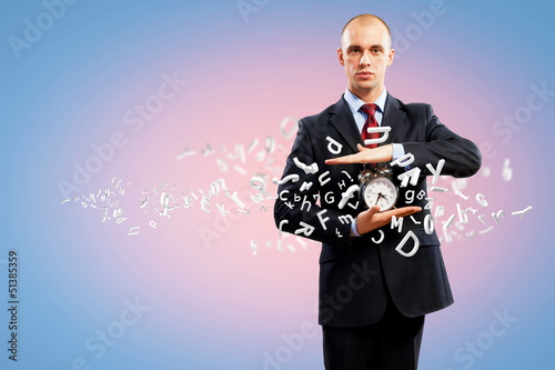 Photo: Business man holding alarmclock Business man holding alarmclock