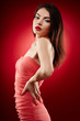 Beautiful brunette standing with hands on hips on red background