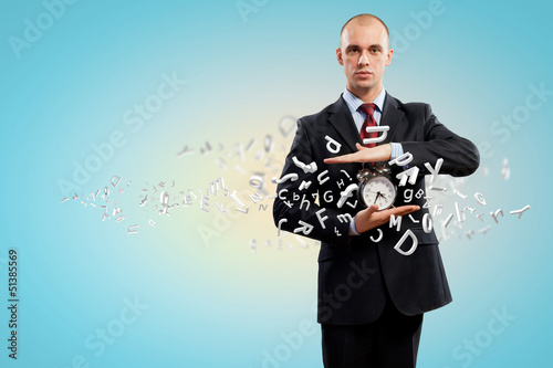 Photo: Business man holding alarmclock Business man holding alarmclock