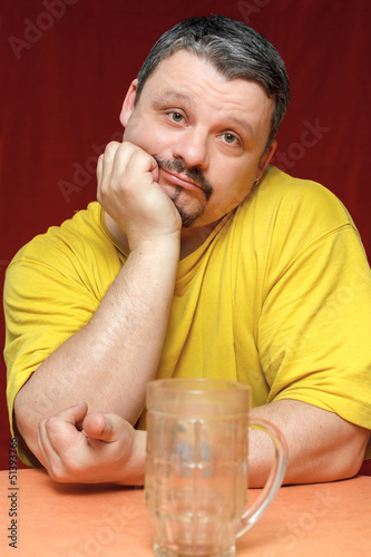 Photo: dark sad man looks at an empty beer mug dark sad man looks at an empty beer mug