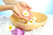 woman hands with wooden bowl of water with flowers,