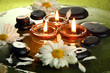 Photo : spa stones with flowers and candles in water on plate spa stones with flowers and candles in water on plate