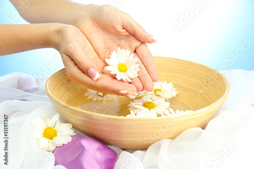 Photo: woman hands with wooden bowl of water with flowers, woman hands with wooden bowl of water with flowers,