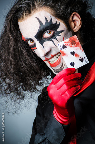 Photo: Evil clown with cards in dark room Evil clown with cards in dark room