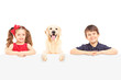 Smiling boy and girl standing behind a blank panel with a Labrad