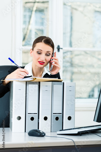 Photo: businesswoman in office makes notes in a file businesswoman in office makes notes in a file