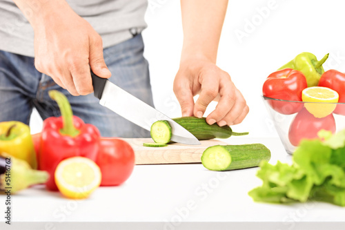 Photo: Male cutting cucumber, preparing salad Male cutting cucumber, preparing salad