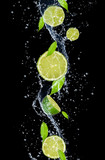 Limes in water splash, isolated on black background