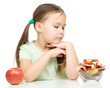 Little girl choosing between apples and sweets