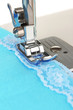 Closeup of sewing machine working part with  blue cloth