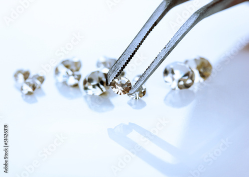 Photo: Beautiful shining crystal (diamond) in the tweezers, isolated Beautiful shining crystal (diamond) in the tweezers, isolated