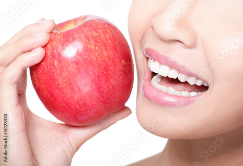 Photo: young woman eating red apple with health teeth young woman eating red apple with health teeth
