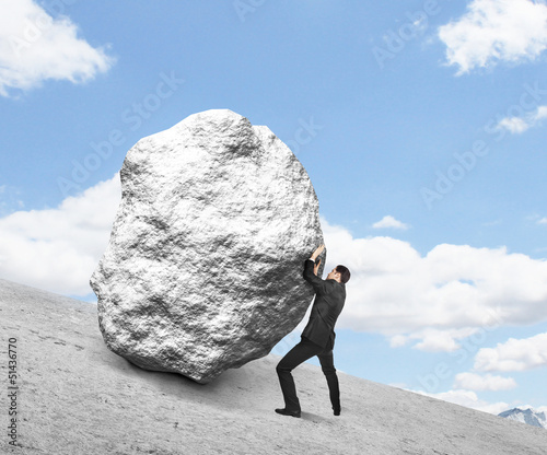 Photo: businessman pushing stone businessman pushing stone