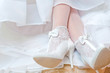 The bride shows white wedding shoes
