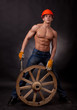 Muscular young man with a wagon wheel on a black background.
